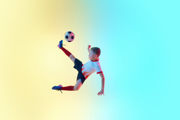 青少年足球运动员在霓虹灯对梯度背景踢球的动态照片。半空中通过。图片下载