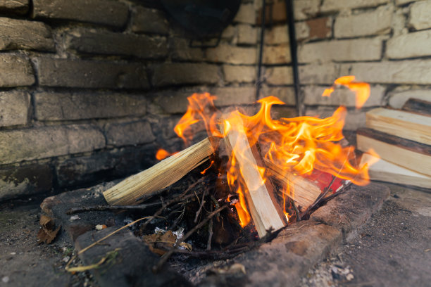 红色的火焰从一棵树的切割，深灰色的煤在一个金属火盆。木柴在火盆里燃烧着明黄色的火焰。火焰准备烧烤满足库存照片…没有人，拷贝空间图片下载