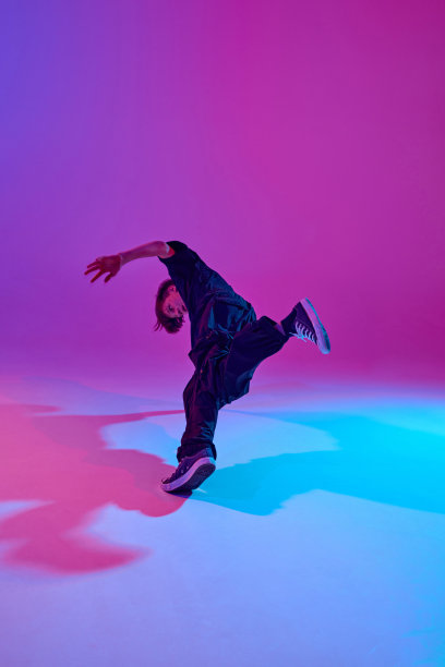 年轻的街头舞者在充满活力的渐变背景下，穿着全黑的霓虹灯，摆出动感的姿势。图片下载
