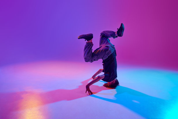 穿着时髦的年轻舞者，在混合的霓虹灯和充满活力的渐变背景下表演头部旋转。图片下载