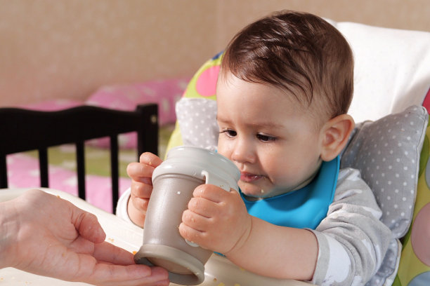 英俊认真甜美的小男孩孩子坐在桌子上从瓶子里喝水，特写图片下载