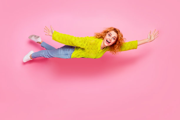 照片中时髦、兴奋、开朗的女人穿着绿色时髦的衣服，在粉红色的背景上飞出空气图片下载