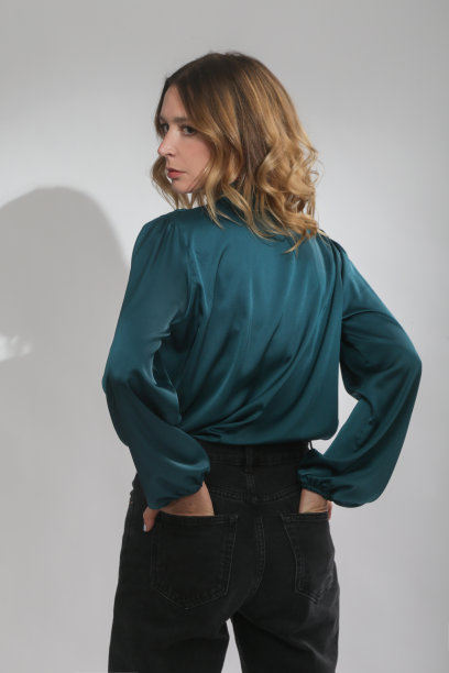 一系列的工作室照片，年轻的女模特穿着绿色绸缎衬衫和黑色裤子图片下载