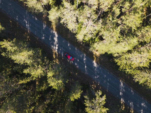 夏日，一辆红色轿车行驶在林间小路上，这是无人机拍摄的照片。图片下载