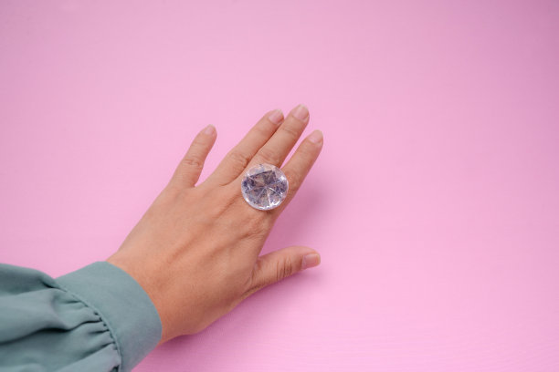 女人的手拿着大假钻石在粉红色的背景图片下载