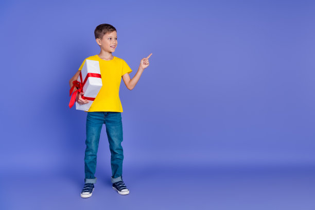 照片正面的青春期前的好男孩穿着时髦的黄色衣服推荐商店商店空的空间孤立在紫罗兰色的背景图片下载