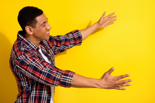 侧面照片的快乐开朗的男人穿着时髦的衣服打开双手看拥抱海报空白空间孤立在黄色的背景图片下载