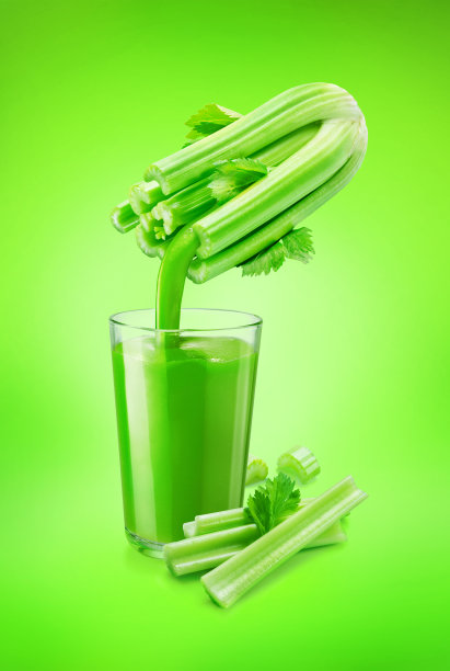 一杯芹菜汁和从绿色背景上分离出来的新鲜芹菜茎上倒出来的果汁。概念上的照片。图片下载