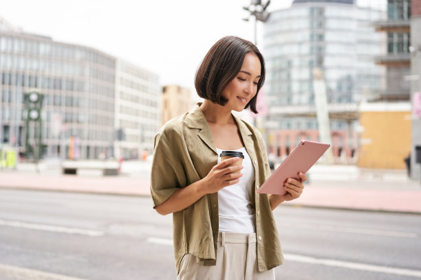 快乐的城市女孩走在街上，在上班的路上用平板电脑和喝咖啡图片下载