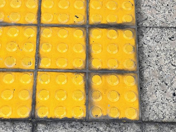 一张黑白背景的人行道上黄色瓷砖的照片。图片下载