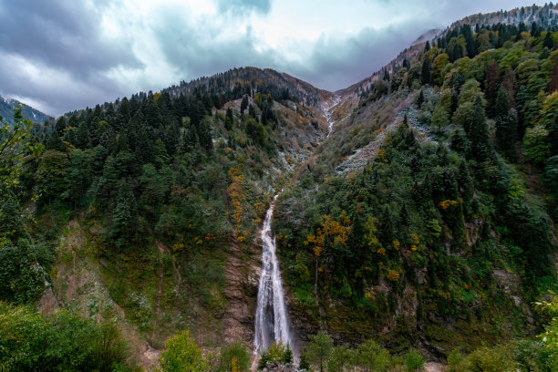 秋天的瀑布照片。从石头中流出的水以瀑布的形式流动。瀑布景观与云。图片下载