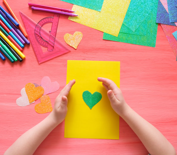 孩子用纸制作贺卡和工艺品。鲜花和爱心作为母亲节、父亲节、生日或情人节的礼物。工艺美术概念。图片下载