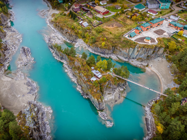 俄罗斯阿尔泰山脉的小岛上的帕特莫斯东正教教堂和横跨卡通河的桥梁的航拍照片。图片下载