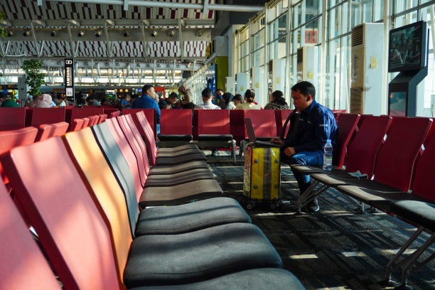 旅客在苏丹哈桑丁望加锡机场航站楼使用笔记本电脑图片下载