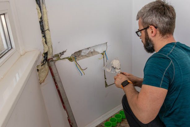 一个人把墙上的插座装在石膏上图片下载