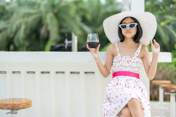 这位年轻的亚洲旅行者穿着传统服装，戴着帽子，参加节日和活动，偶尔在酒店附近喝一杯当地的葡萄酒。图片下载