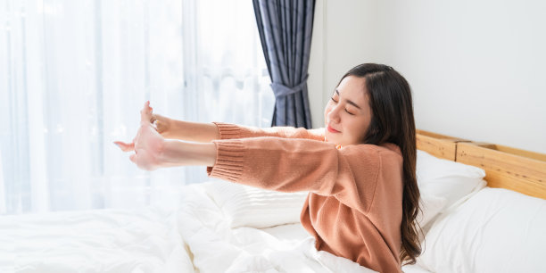 年轻的亚洲女人睡在床上，醒来。图片下载