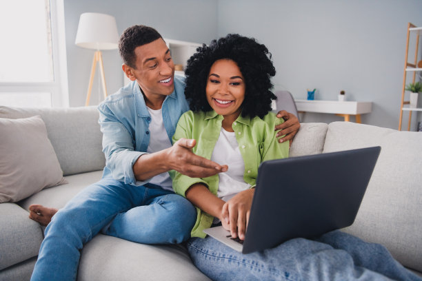 漂亮的年轻男子的照片女孩坐在沙发远程工作上网本购物现代室内室内舒适的日光公寓客厅图片下载