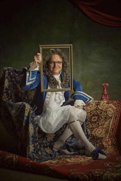 一位身穿巴洛克风格服装的老人手持华丽的相框，背景是复古的工作室。自画像。图片下载