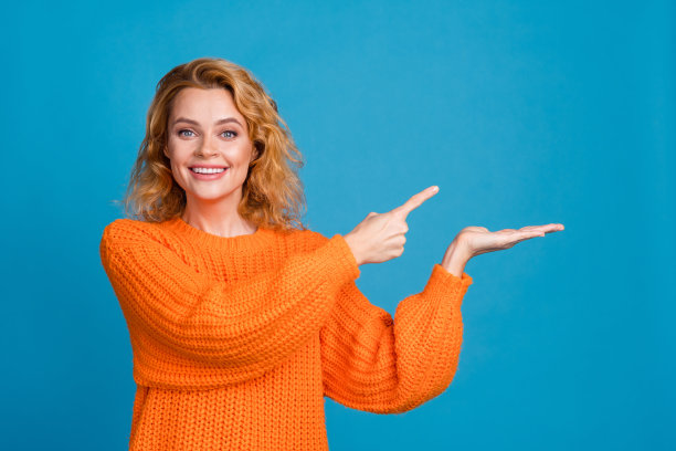 照片中，可爱的美女穿着时尚的冬装，手持横幅，空白的空间被隔离在蓝色的背景上图片下载