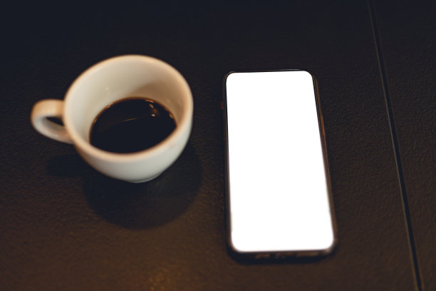 手机空白的白色屏幕和一杯咖啡的照片。模板概念与智能手机，孤立的模拟图片与杯子的饮料。图片下载
