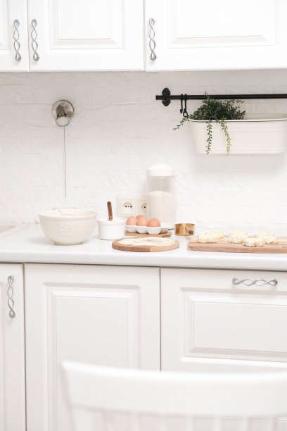 家庭厨房内部。在现代厨房的餐桌上，有面团和抹刀的碗，鸡蛋和糖碗，餐巾。图片下载
