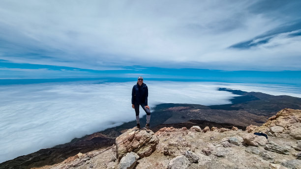 泰德——站在特内里费岛泰德Pico del Teide火山山顶岩石上的快乐女人的正面照片。图片下载