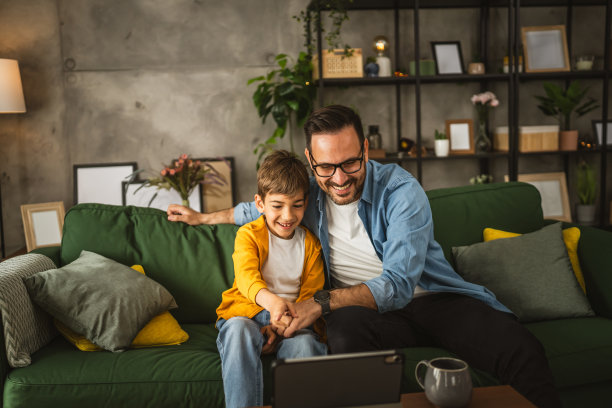 父子俩在家里用平板电脑看电影或卡通片图片下载