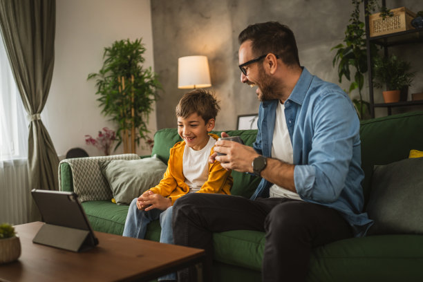父子俩在家里用平板电脑看电影或卡通片图片下载
