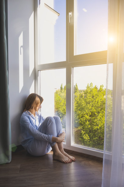 一个女人赤脚坐在地板上的垂直照片。地暖和智能供暖的概念。图片下载