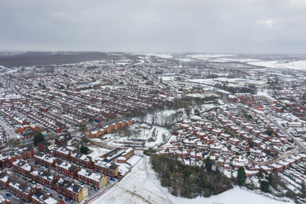 这是英国利兹市下雪天的航拍照片，展示了冬季比斯顿村一排排屋顶被雪覆盖的排屋图片下载