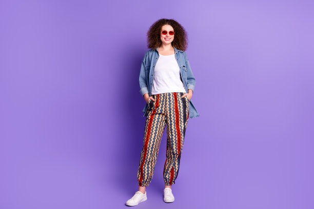 酷漂亮女孩的全身照片，把双手口袋穿牛仔衬衫孤立在紫罗兰色的背景图片下载