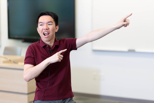 一个穿红衬衫的学生在教室里开心地指着图片下载