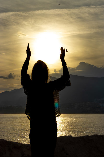 这张照片捕捉到了一个女人在充满活力的日落画布上引人注目的剪影图片下载