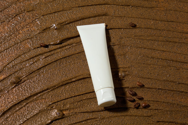 平整的白色化妆管衬着棕色去角质霜的质感，创意照片从俯视图拍摄，有许多空白空间添加设计元素，复制空间图片下载