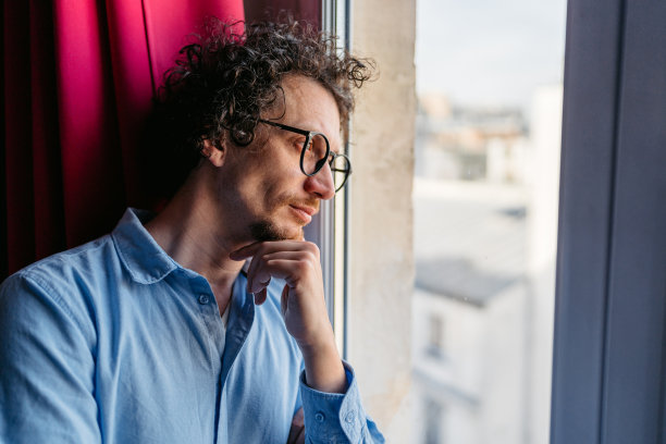 法国巴黎，一名中年男子望向窗外的公寓图片下载