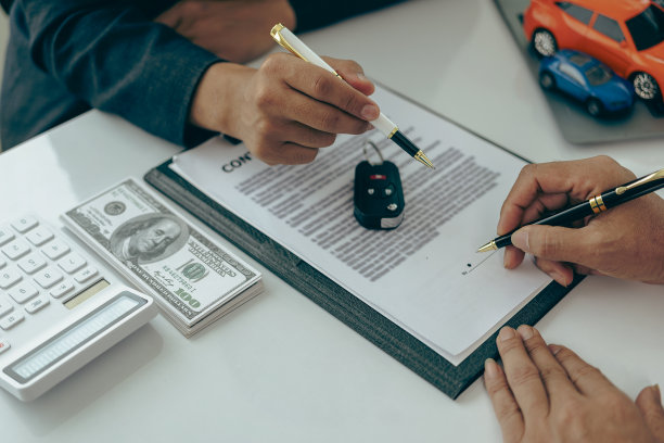一个销售人员带着一辆小车和车钥匙，坐在桌子旁介绍顾客的特写照片。汽车经销商销售新车主已经签订了一份汽车销售和租赁合同。图片下载