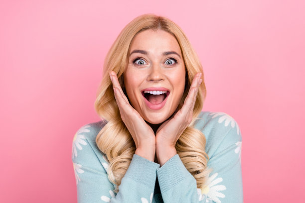 梦幻女子的照片，波浪发型，穿着印花开衫，抱着大红色的心，在粉红色的背景上看起来空空荡荡，与世隔绝图片下载