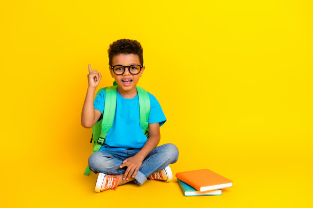 聪明开朗的青春期前男孩穿着蓝色t恤阅读小说孤立的黄色背景的全身照片快乐兴奋的青春期前男孩穿着蓝色t恤阅读故事，手指向上伸出空白的空间孤立的黄色背景图片下载