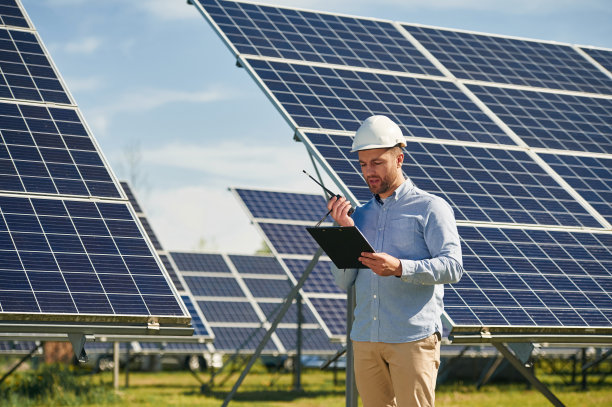 使用对讲机和手持记事本。白天在户外使用光伏太阳能电池板的工程师图片下载