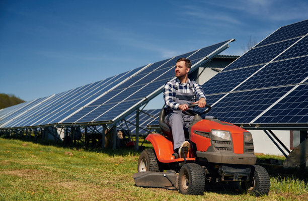 红色的割草机。白天在户外使用光伏太阳能电池板的工程师图片下载