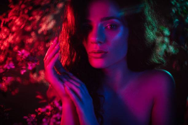 一个梦幻般的女孩在霓虹灯和五彩缤纷的花丛中的照片。幻想、童话、魔法和仙女的概念。图片下载