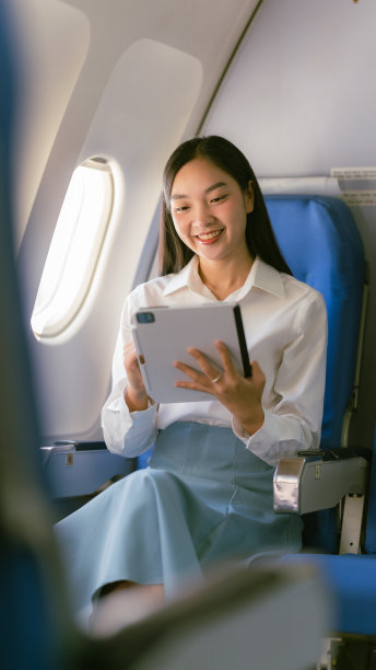亚洲女性在飞机上靠窗坐着拿着平板电脑，旅行和商业概念图片下载