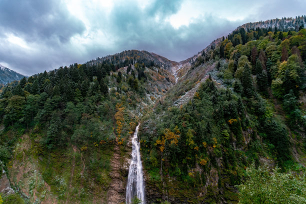 秋天的瀑布照片。从石头中流出的水以瀑布的形式流动。瀑布景观与云。图片下载