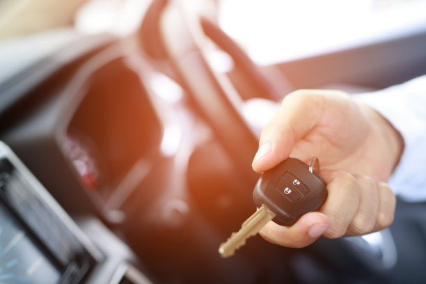 车钥匙，商人把钥匙交给展厅背景的另一个人。卖方经销商信用利息支付或分期购车的概念。图片下载