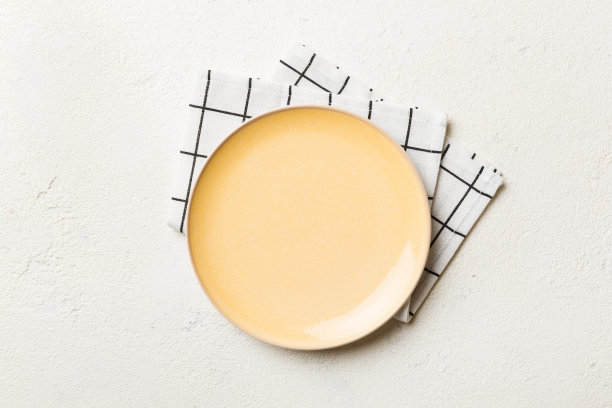 在彩色背景上的俯视图空圆形黄色盘子在桌布上的食物。空盘子放在餐巾上，为你的设计留出空间图片下载