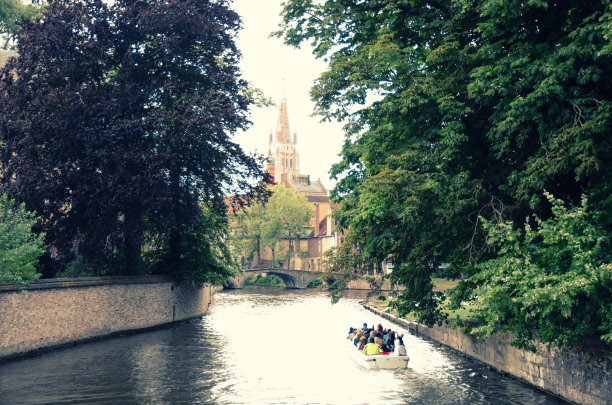 Bakkersrei水渠与游客船，树木在银行，贝居尼桥，圣母教堂建筑在布鲁日老城区，布鲁日市历史中心，复古照片，西佛兰德斯，比利时图片下载