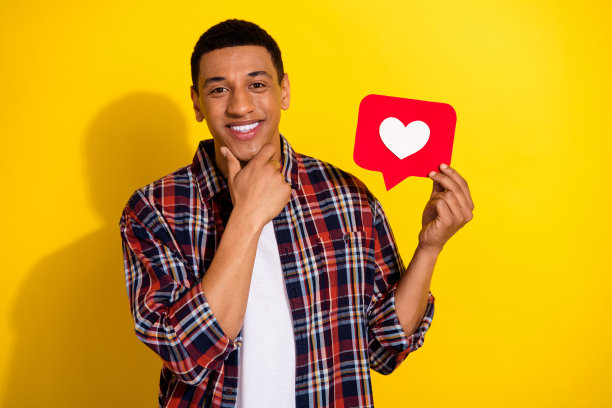 有吸引力的流行博主的照片漂亮的男人穿着时尚的格纹衣服，手拿红纸卡像孤立的黄色背景图片下载