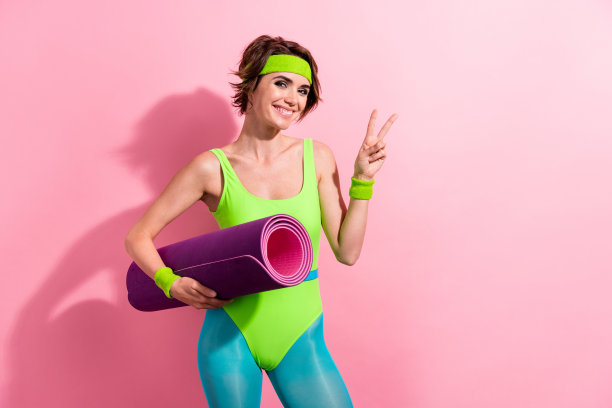 照片的专业瑜伽普拉提教练持有健身垫使v标志孤立柔和的颜色背景图片下载