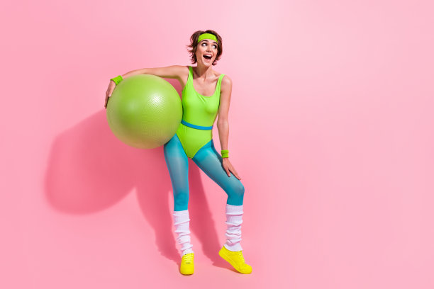 照片兴奋的教练拿着健身球享受激烈的瑜伽训练孤立的柔和的颜色背景图片下载
